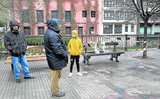 Tres personas observan el lugar del siniestro ayer a la mañana, mientras en un banco permanecen dos ramos de flores en memoria de los fallecidos.