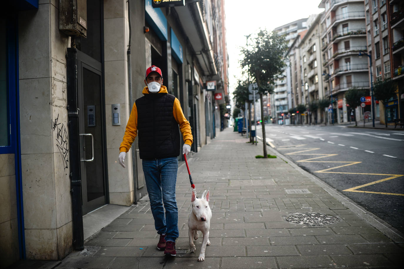 Un hombre protegido con una mascarilla pasea a su perro en Portugalete.