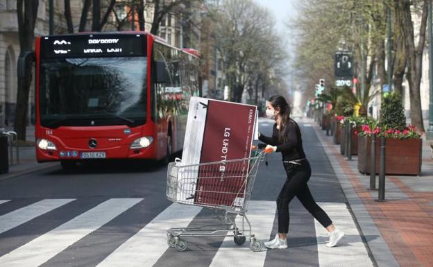 Imagen principal - Una trabajadora lleva una tele desde Gran Vía 12 al parking del edificio principal para atender una compra on-line