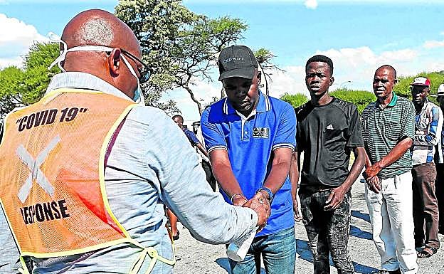 Un funcionario sanitario rocía con desinfectante las manos de viajeros en Sudáfrica.