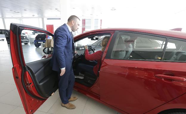 Un comercial enseña un coche a una clienta.