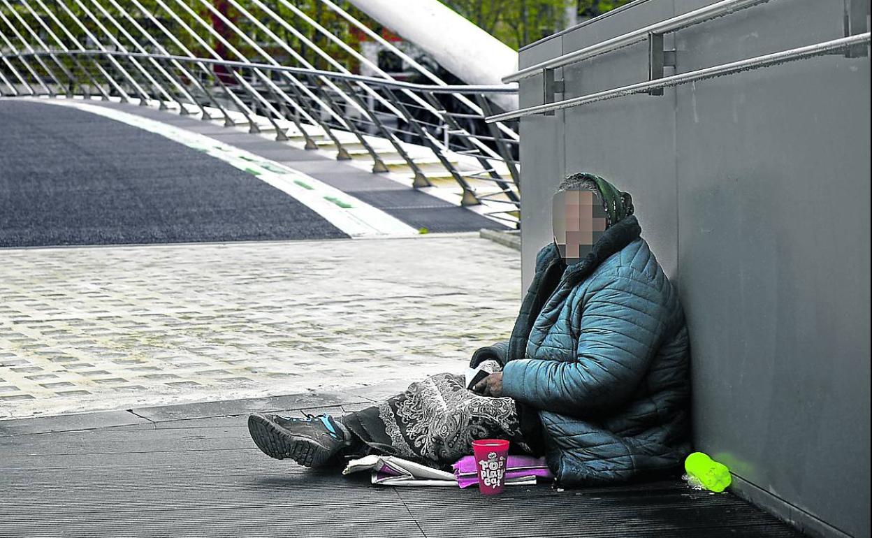 Una mujer pide limosna ayer por la mañana en el puente Zubi Zuri de Bilbao.