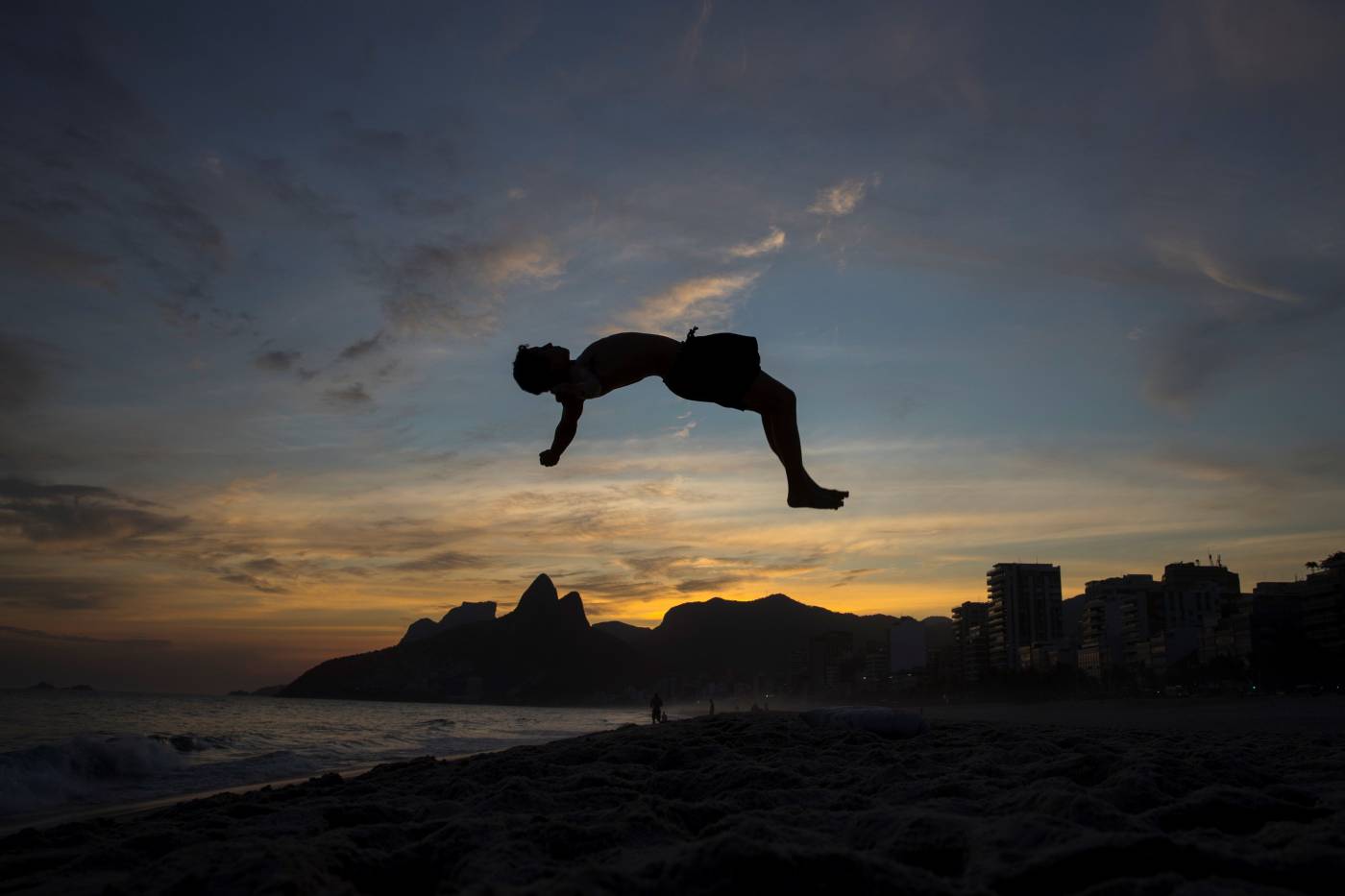 El joven franco-brasileño Guido Tercio, de 18 años, practica saltos en la arena de la playa de Ipanema, en Río de Janeiro (Brasil). El fin de la tarde llevó algunas personas a la playa a pesar de la cuarentena que rige en varias ciudades del país. 