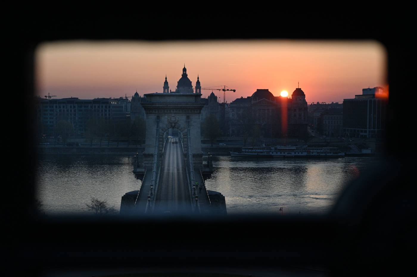 El sol sale detrás del puente húngaro más antiguo, el 'Lanchid' (Puente de las Cadenas) en Budapest, en medio de la nueva pandemia de coronavirus / Covid-19.