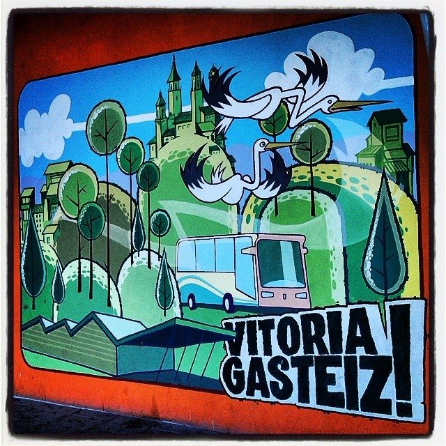 En Salburua puede verse este mural, donde comparten protagonismo la nueva estación de autobuses, un urbano, edificios emblemáticos de la ciudad, numerosos árboles y un par de cigüeñas que parecen estar buscando el parque y las balsas con las que el barrio comparte nombre.