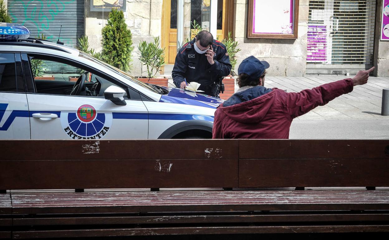 Un ertzaina redacta un parte de denuncia a un transeúnte en Vitoria. 