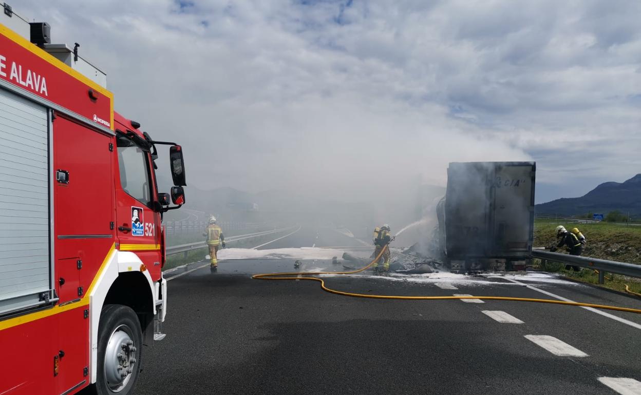 Una dotación de bomberos apaga las llamas en el remolque del camión.