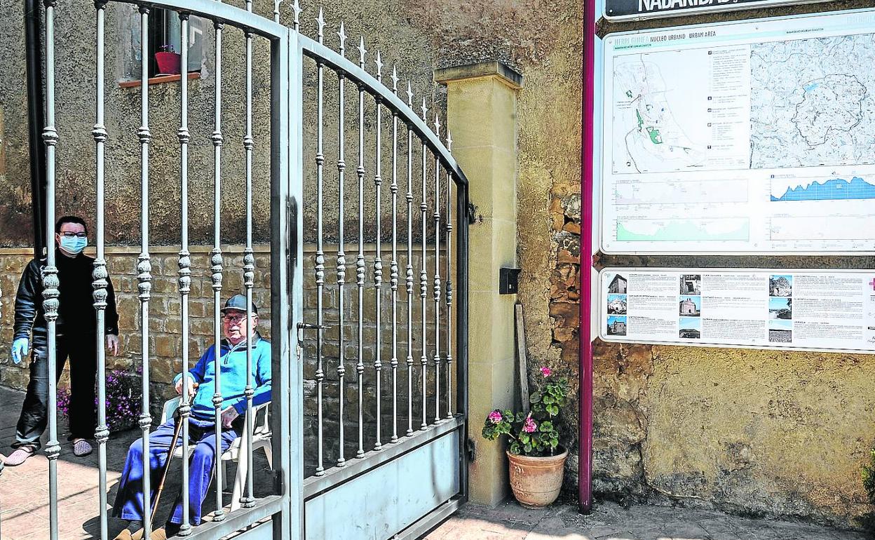 Andrés Fernández descansa en una silla a la entrada de su casa de Navaridas en presencia de su hija Laura.