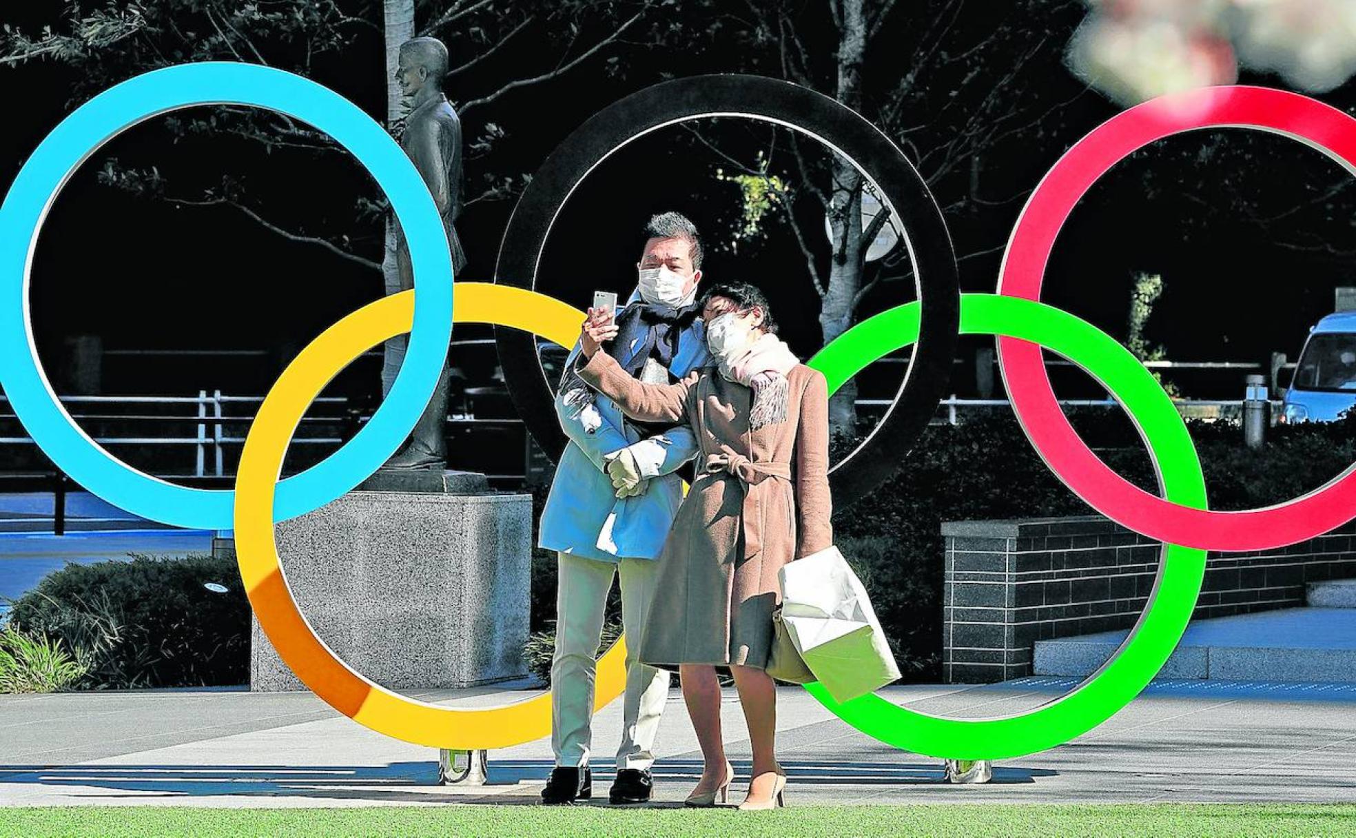 Una pareja se hace un selfie con mascarilla ante la sede del comité olímpico de Japón, en Tokio. 