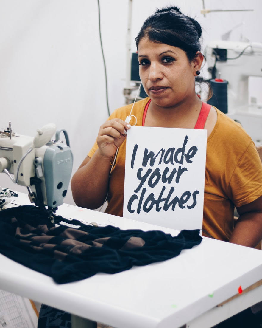 Una trabajadora sostiene el cartel 'Yo hago tu ropa'.