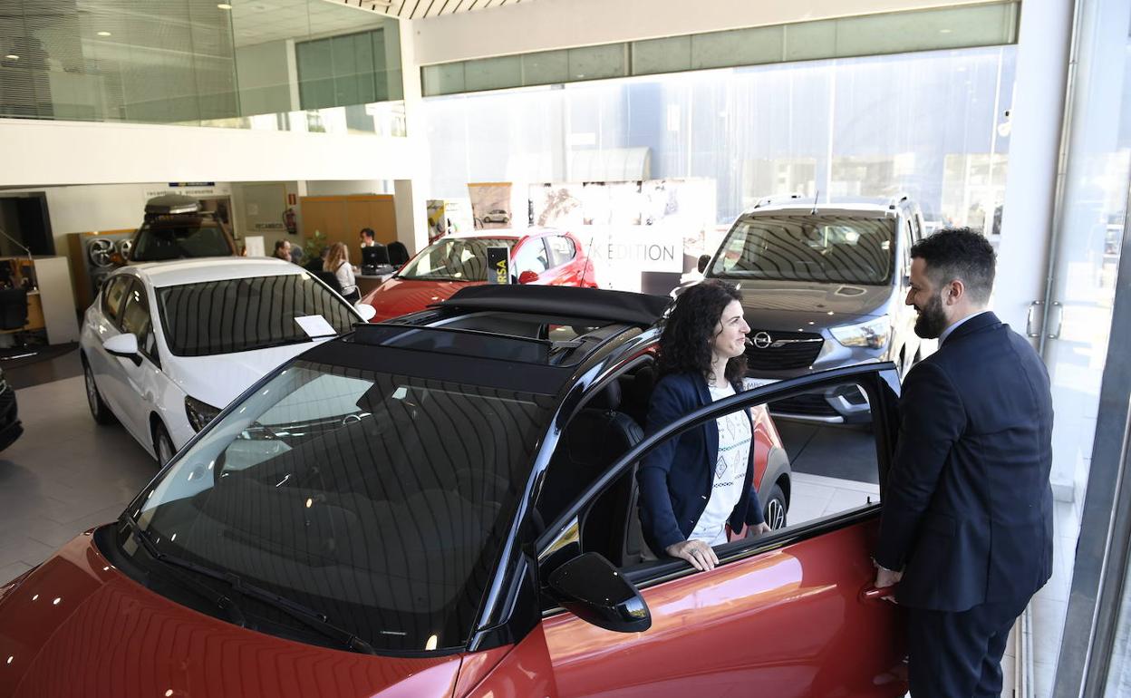 Un comercial de un concesionarios enseña un coche una clienta 