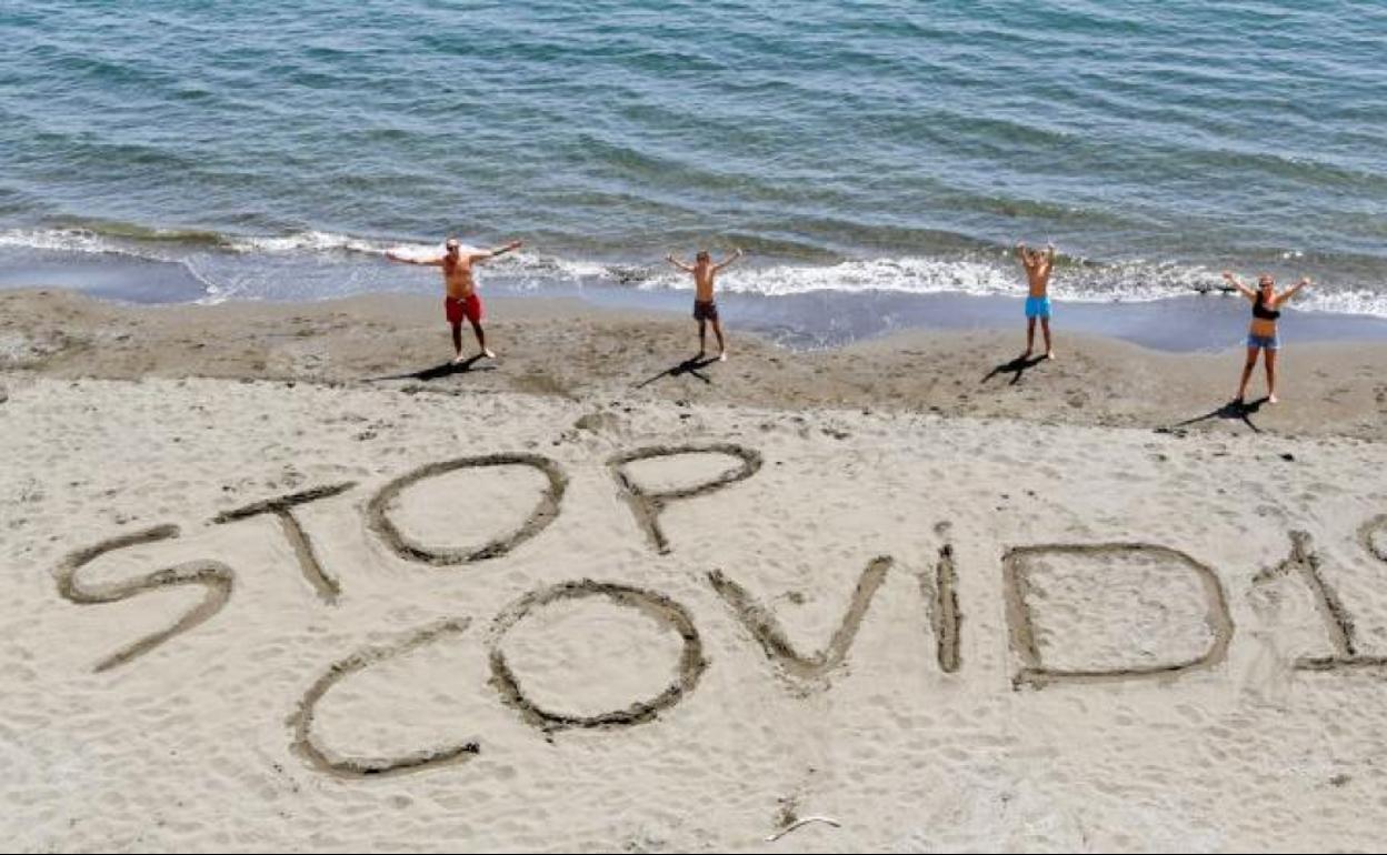 Una familia escribe la frase 'Stop Covid-19´ en la arena de una playa de Nápoles, Italia. 