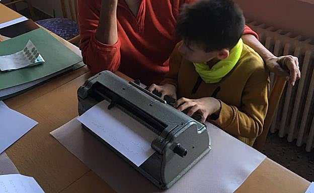 Un niño ciego escribe en braille con la máquina de escribir Perkins.