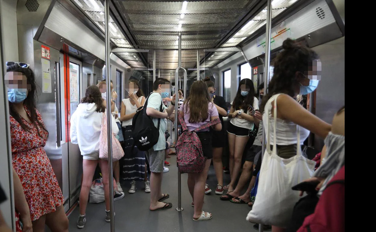 Jóvenes regresan en metro a sus casas tras acudir a la playa este viernes.