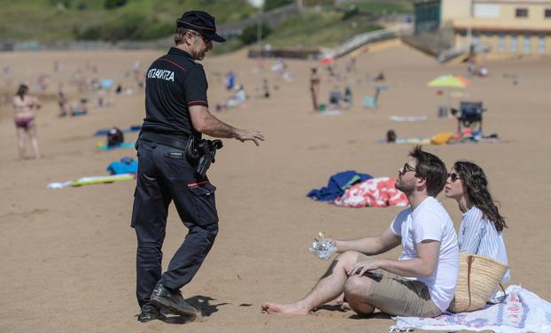 Un agente informa a una pareja de las restricciones en la playa de La Arena. 