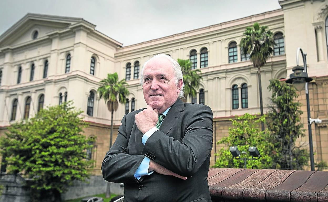 El rector de Deusto, José María Guibert, en el campus universitario. A la derecha, muestra un pin de la institución académica. 