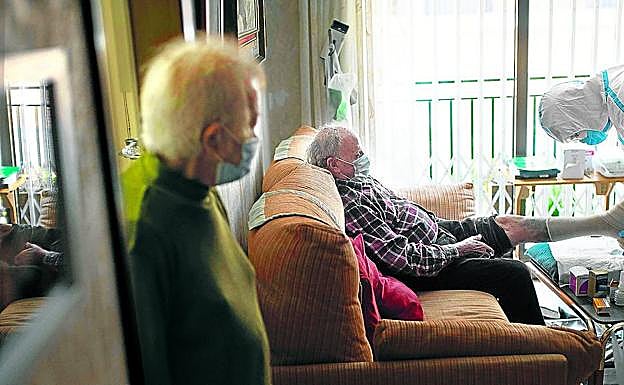 Un sanitario atiende a un paciente de Covid-19 en su casa de Barcelona. AFP