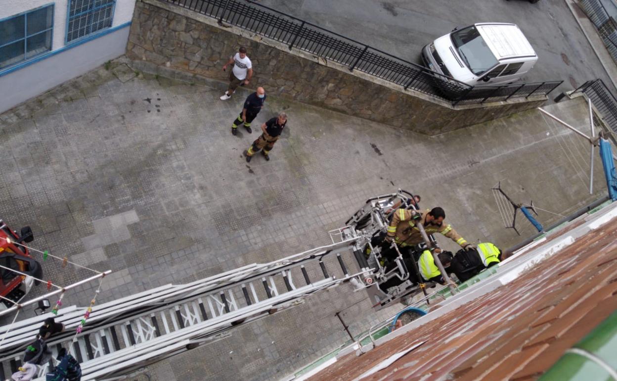 Bomberos y Policía en una ventana de la vivienda.