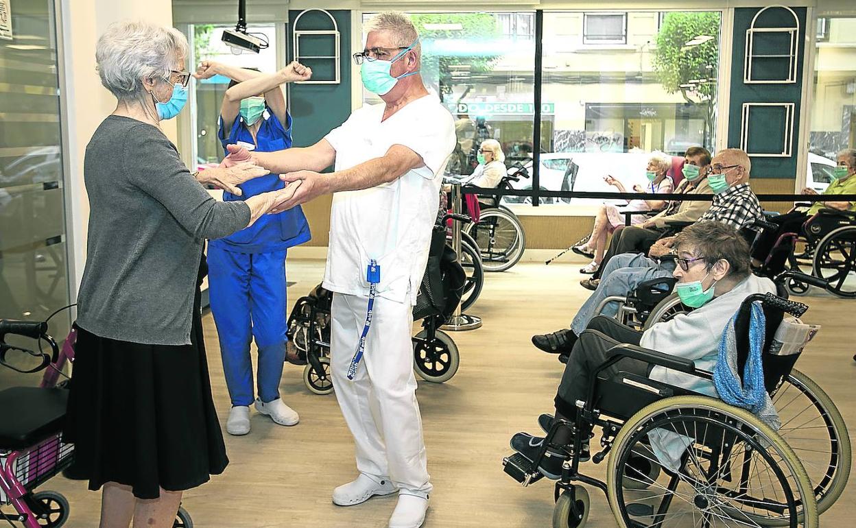 Un sanitario de la residencia Olimpia de Bilbao saluda a una residente en una de las salas comunes del centro. 