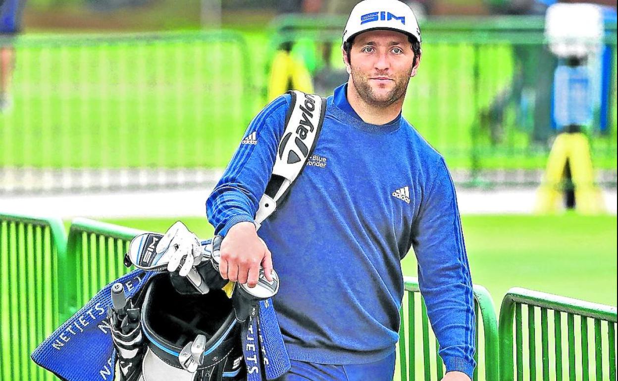 Jon Rahm carga con su bolsa camino del campo de prácticas. 