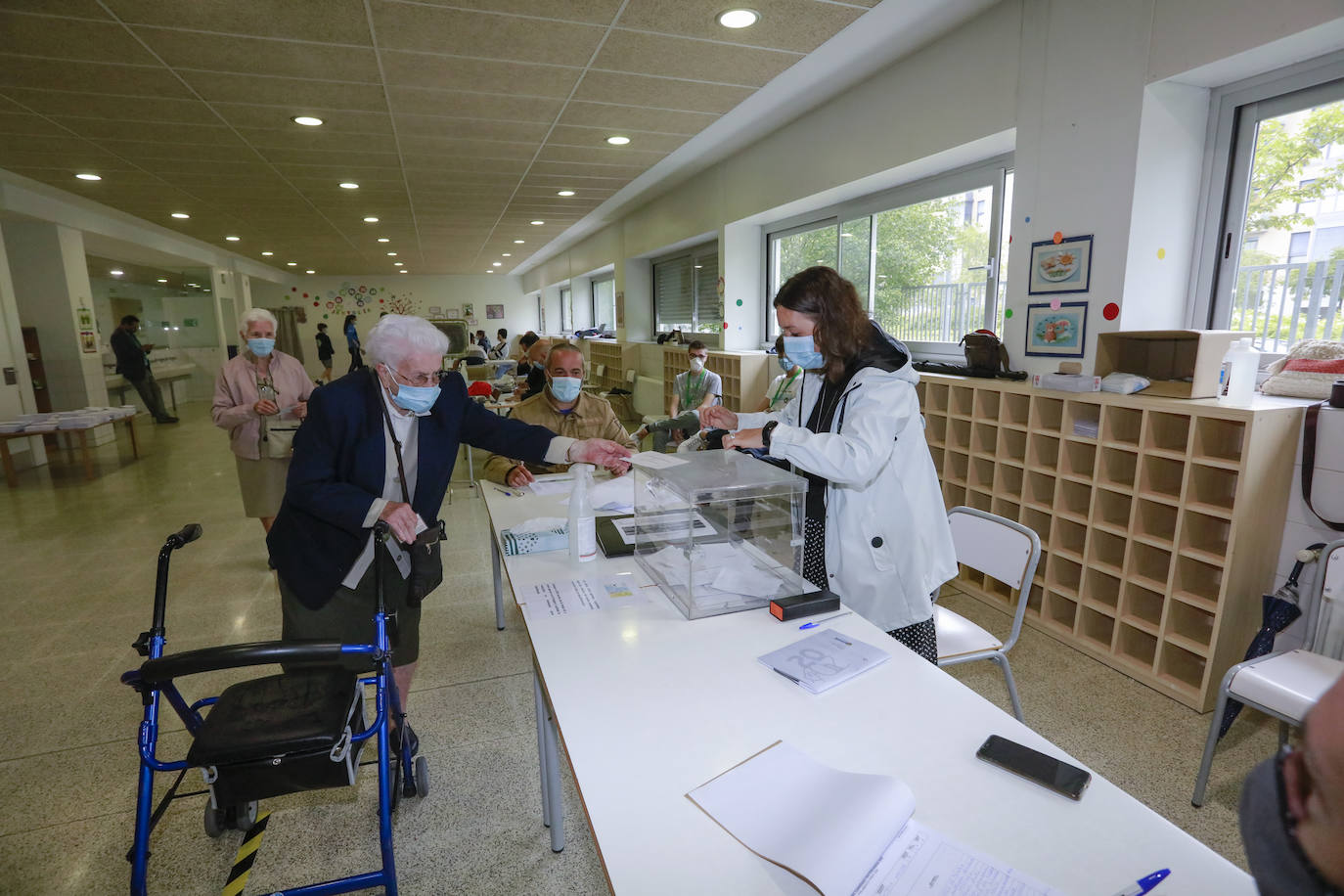 Una mujer introduce su papeleta, guardando la distancia de seguridad, en una mesa electoral del barrio de Ibaiondo.