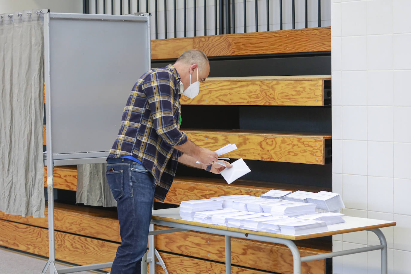 Un ciudadano selecciona su papeleta entre las opciones dispuestas sobre la mesa situada en el colegio de Ibaiondo, en Vitoria.