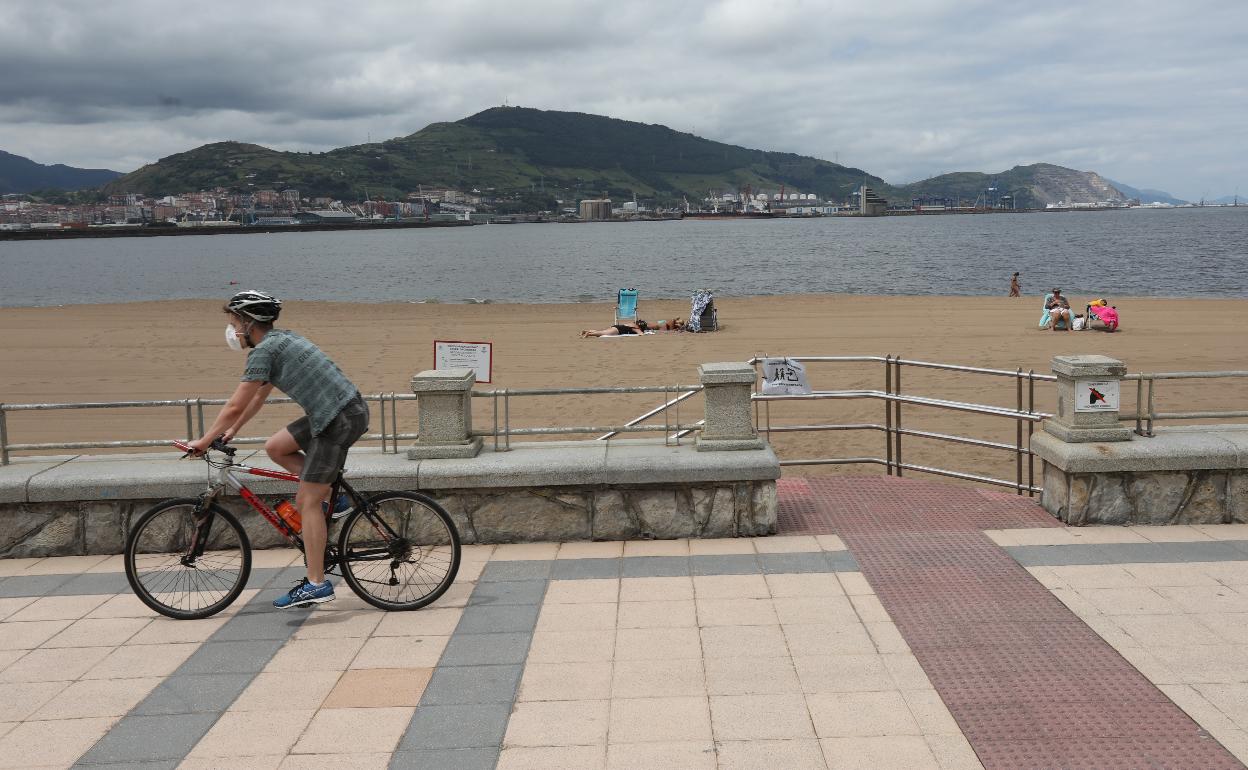 Un cicilista pasa por la playa de Ereaga en Getxo. 