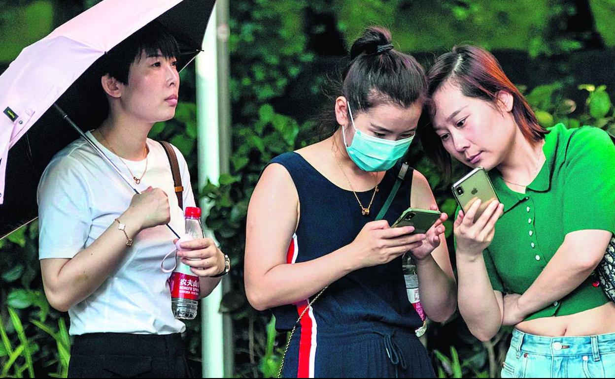 Jóvenes chinas utilizan la aplicación TikTok en sus móviles en Shanghái.