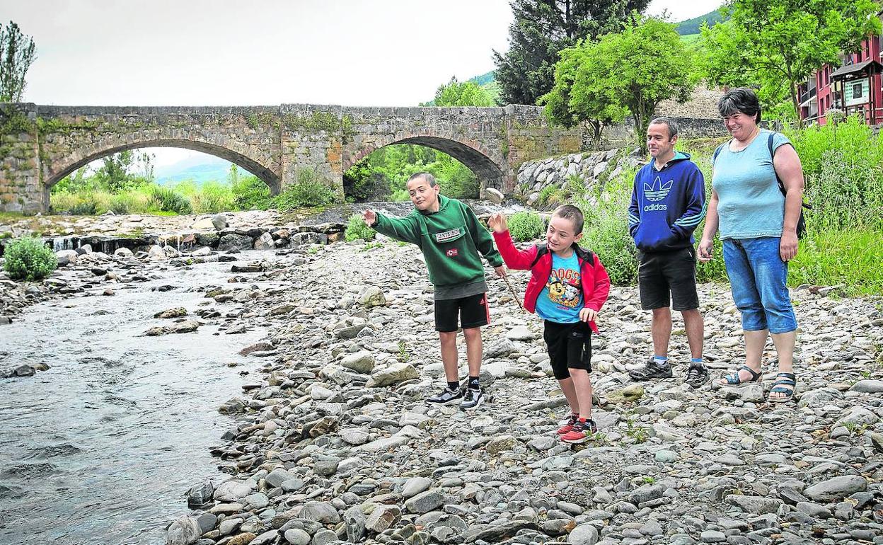¡Que salpique! Aitor y Ander tiran piedras al Oja bajo la mirada de sus padres. El reportaje se hizo antes de que se decretase el uso obligado de la mascarilla.
