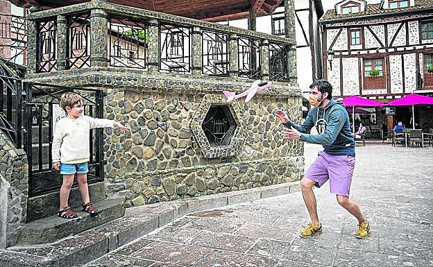 En el quiosco. Mikel y su hijo juegan con un avioncito en la plaza. 