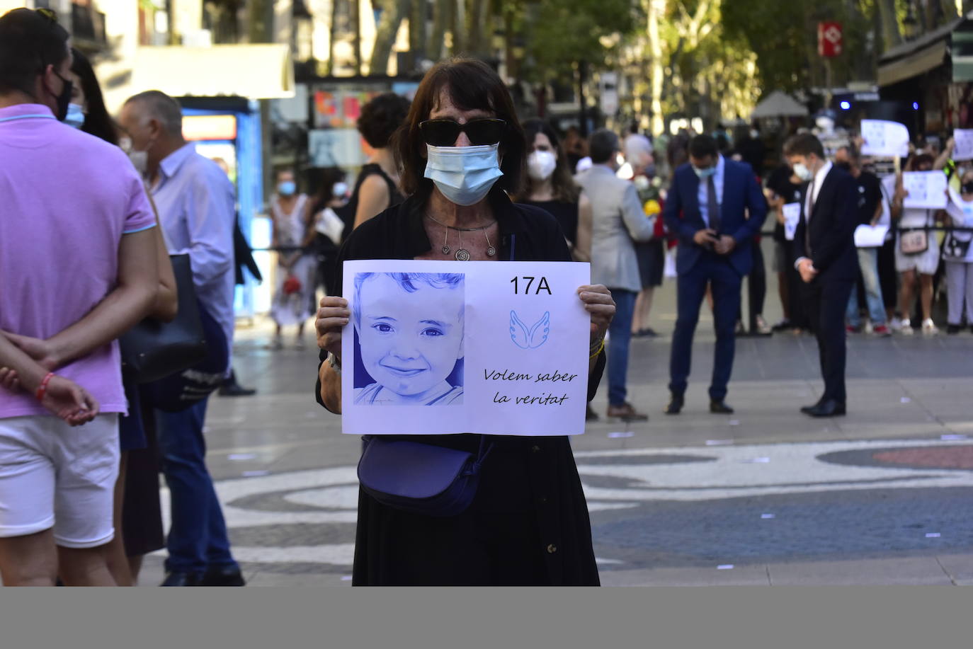 Una mujer protegida con mascarilla sostiene un cartel en recuerdo a las 16 personas fallecidas el 17 de agosto de 2017 en los atentados de Barcelona y Cambrils durante el homenaje y minuto de silencio celebrado en Las Ramblas con motivo del tercer aniversario del ataque. 