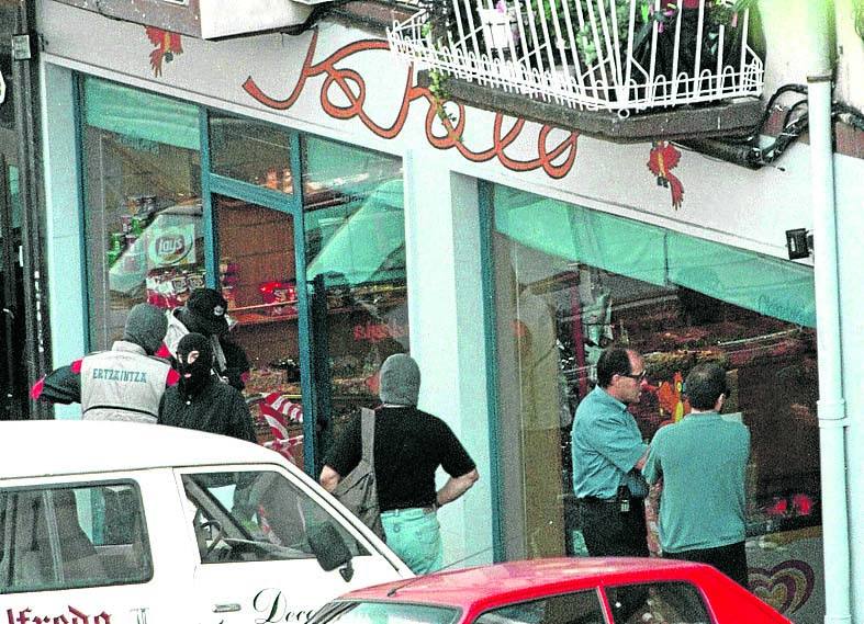 Agentes de la Ertzaintza custodian el exterior de 'Kokolo', la tienda de golosinas que regentaba Indiano y donde se perpetró el atentado. 