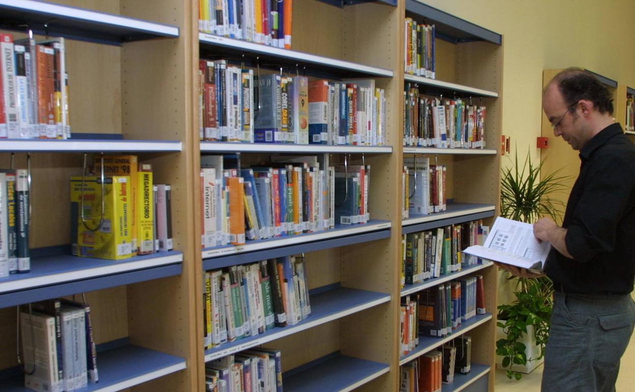 Una persona consulta uno de los libros de la biblioteca. 