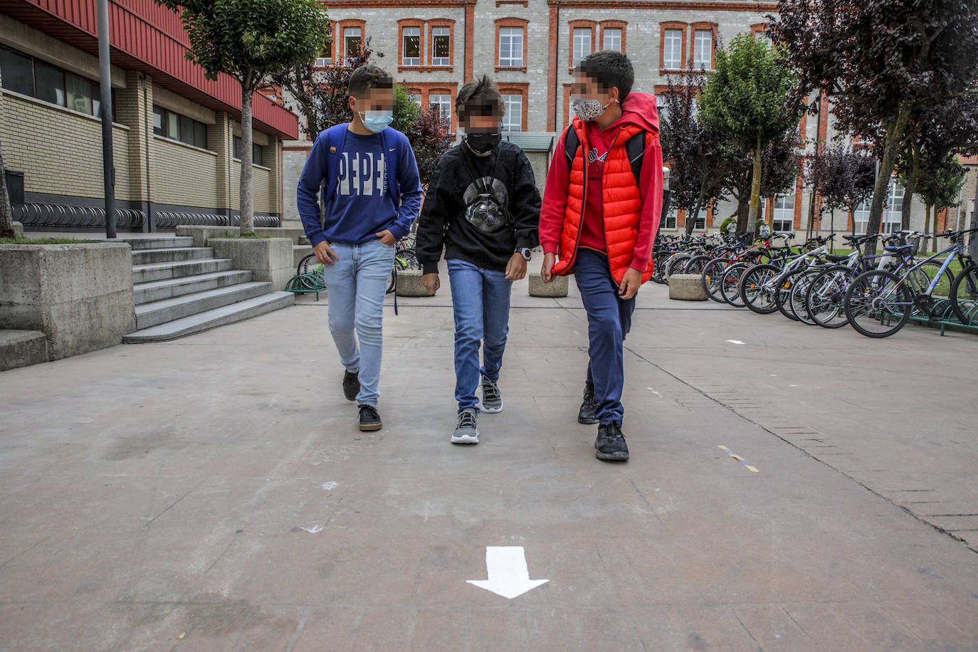 Tres jóvenes estudiantes de Corazonistas siguen las flechas que marcan los nuevos itinerarios trazados en el centro escolar de Vitoria.