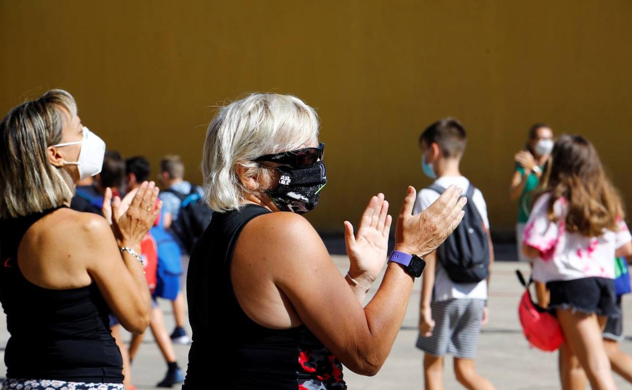 Madres esperan con la mascarilla a sus hijos a la salida del colegio.