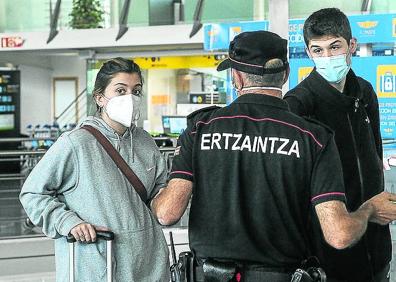 Imagen secundaria 1 - Algunos de los 115 taxistas que trabajan en el aeropuerto aguardan la llegada de viajeros. Una pareja pide información a un ertzaina. La gran mayoría de las tiendas y bares del aeropuerto están cerrados.