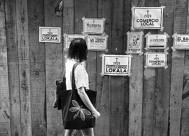 Una viandante se detiene frente a las esquelas de los comercios locales.
