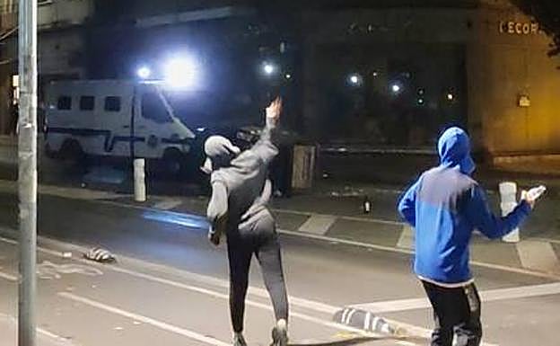 Jóvenes reciben a botellazos a las furgonetas de la Brigada Móvil en Portal de Arriaga el pasado sábado. 
