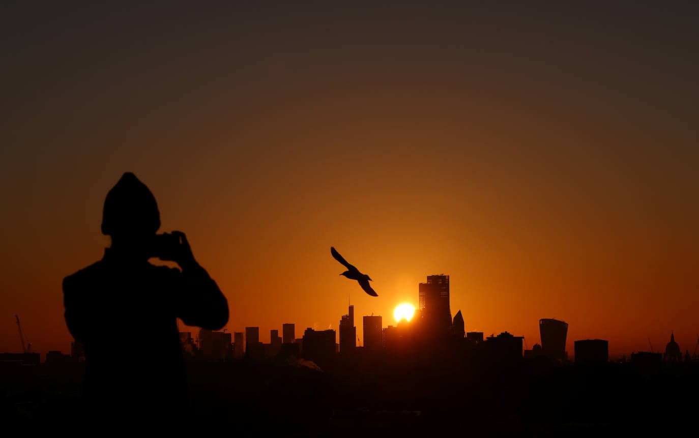 Una persona toma una fotografía del horizonte de Londres desde Primrose Hill, mientras sale el sol en Londres, Gran Bretaña.