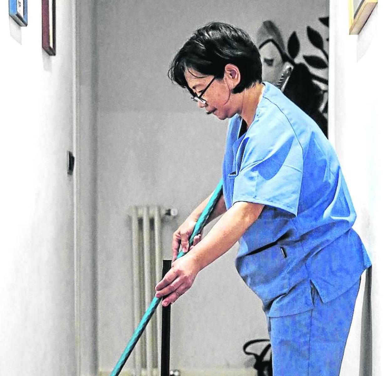 Una empleada del hogar limpia una casa. 