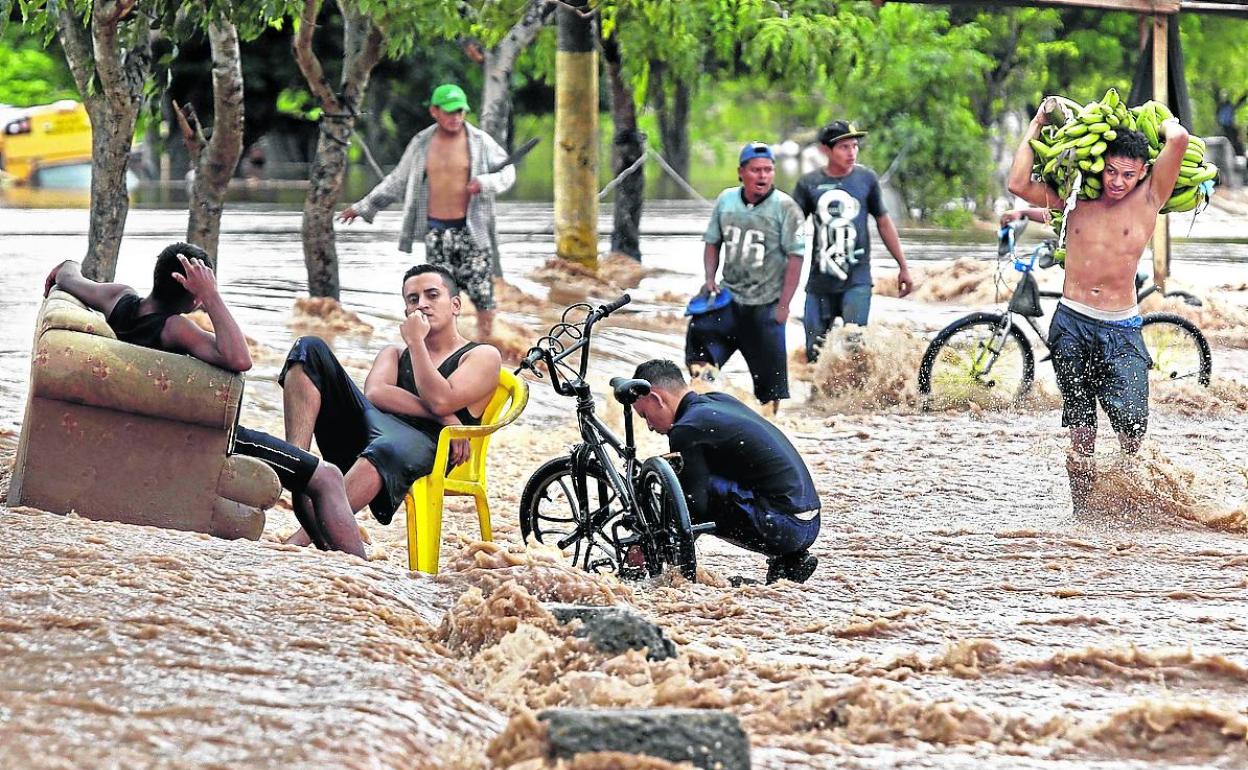 Jóvenes aguardan en una carretera inundada por 'Iota' en el departamento de Yoro, en Honduras. 