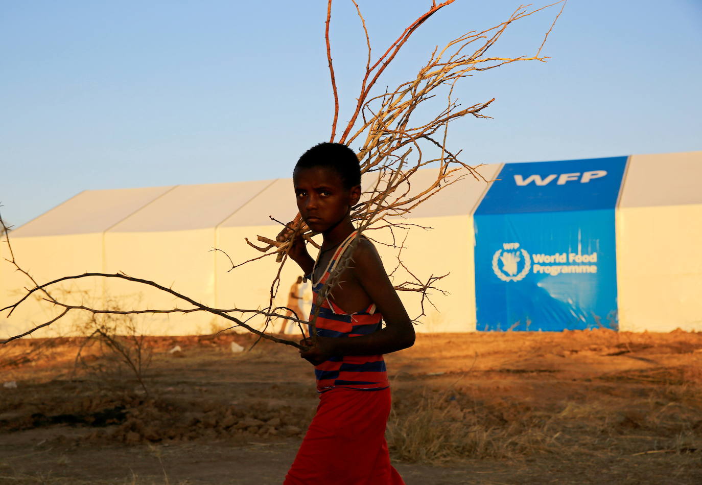 Un refugiado etíope que huye de los combates en curso en la región de Tigray, pasa frente a una carpa del programa mundial de alimentos, en el campamento de Um-Rakoba, en la frontera entre Sudán y Etiopía.