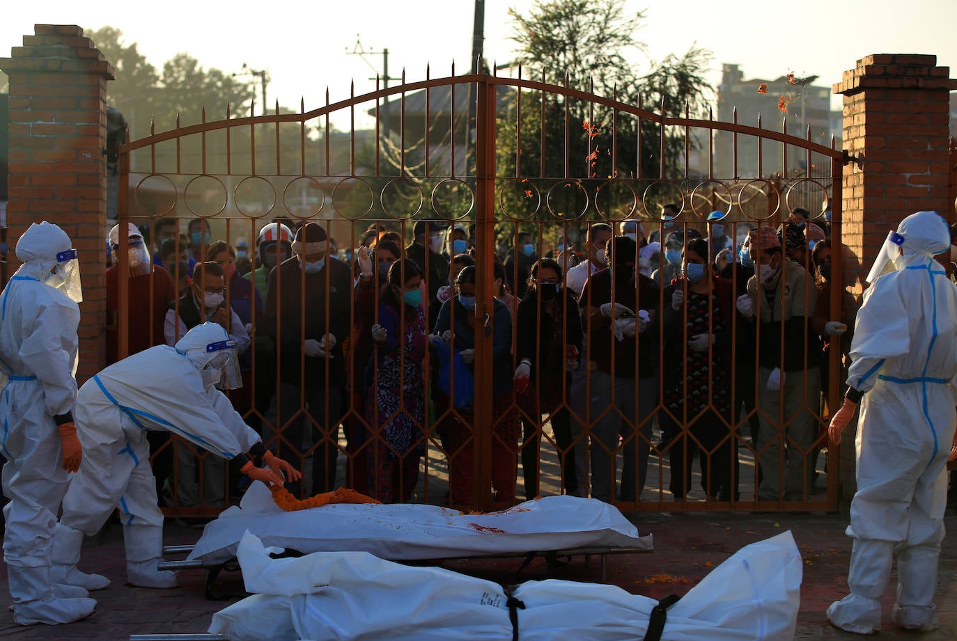 Una mujer soldado ofrece una guirnalda en el cuerpo de una víctima del coronavirus proporcionada por los miembros de la familia en el crematorio.