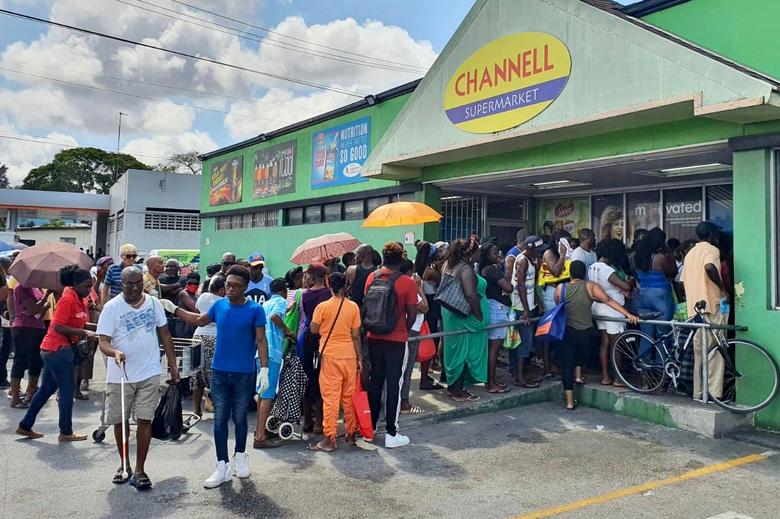 Barbados. Los compradores hacen fila en un supermercado antes del toque de queda de 24 horas, que se extiende hasta el 14 de abril, a partir de las 8 pm en St Michael, Barbados, el 3 de abril de 2020. Los ciudadanos podrán aventurarse solo para comprar alimentos y medicamentos. , obtener efectivo en cajero automático o trabajar en un servicio imprescindible. 