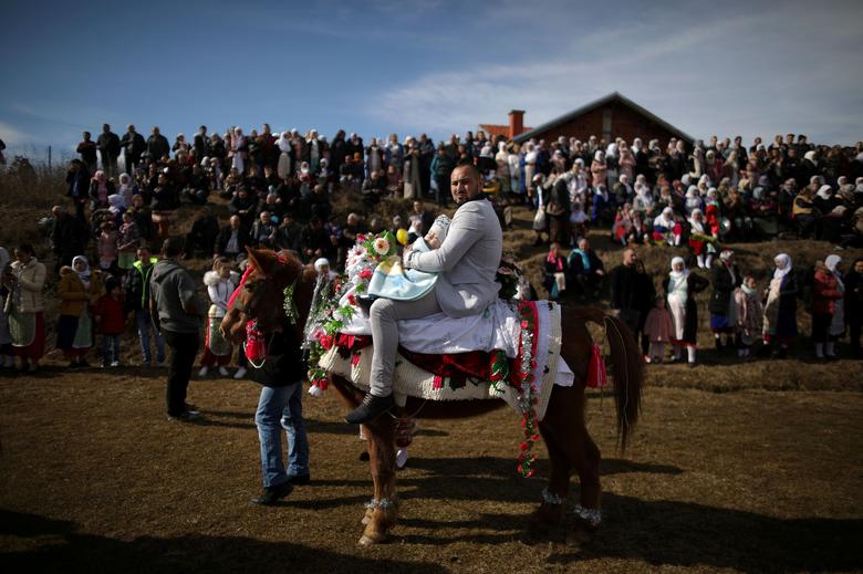 Bulgaria. Un musulmán lleva a su hijo a caballo mientras asisten a un ritual antes de una ceremonia de circuncisión masiva en el pueblo de Ribnovo.