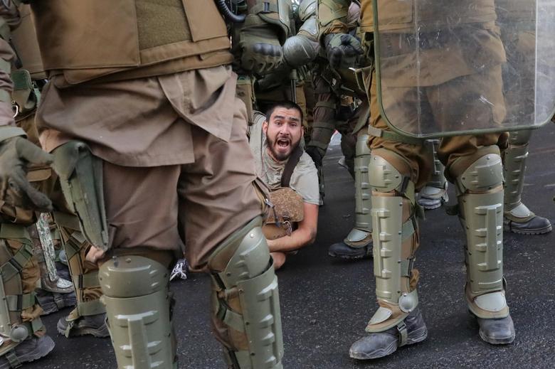 Chile. Un hombre es rodeado por policías antidisturbios durante una protesta convocada por estudiantes de secundaria contra el gobierno chileno y el sistema de educación pública al comenzar el año académico, en Santiago.