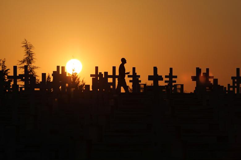 Chipre. La silueta de un hombre contra la puesta de sol mientras pasa junto a las tumbas de los soldados muertos en la invasión turca de Chipre en 1974 en el cementerio militar Tymvos Macedonitissas en Nicosia.