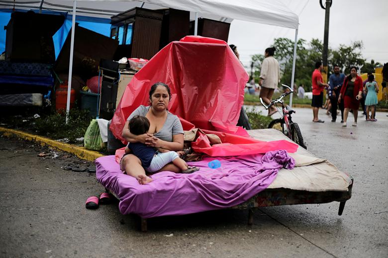 Honduras. Una mujer amamanta a su hijo mientras se sienta en su cama afuera de un área inundada durante el paso de la tormenta Eta, en La Lima, Honduras.