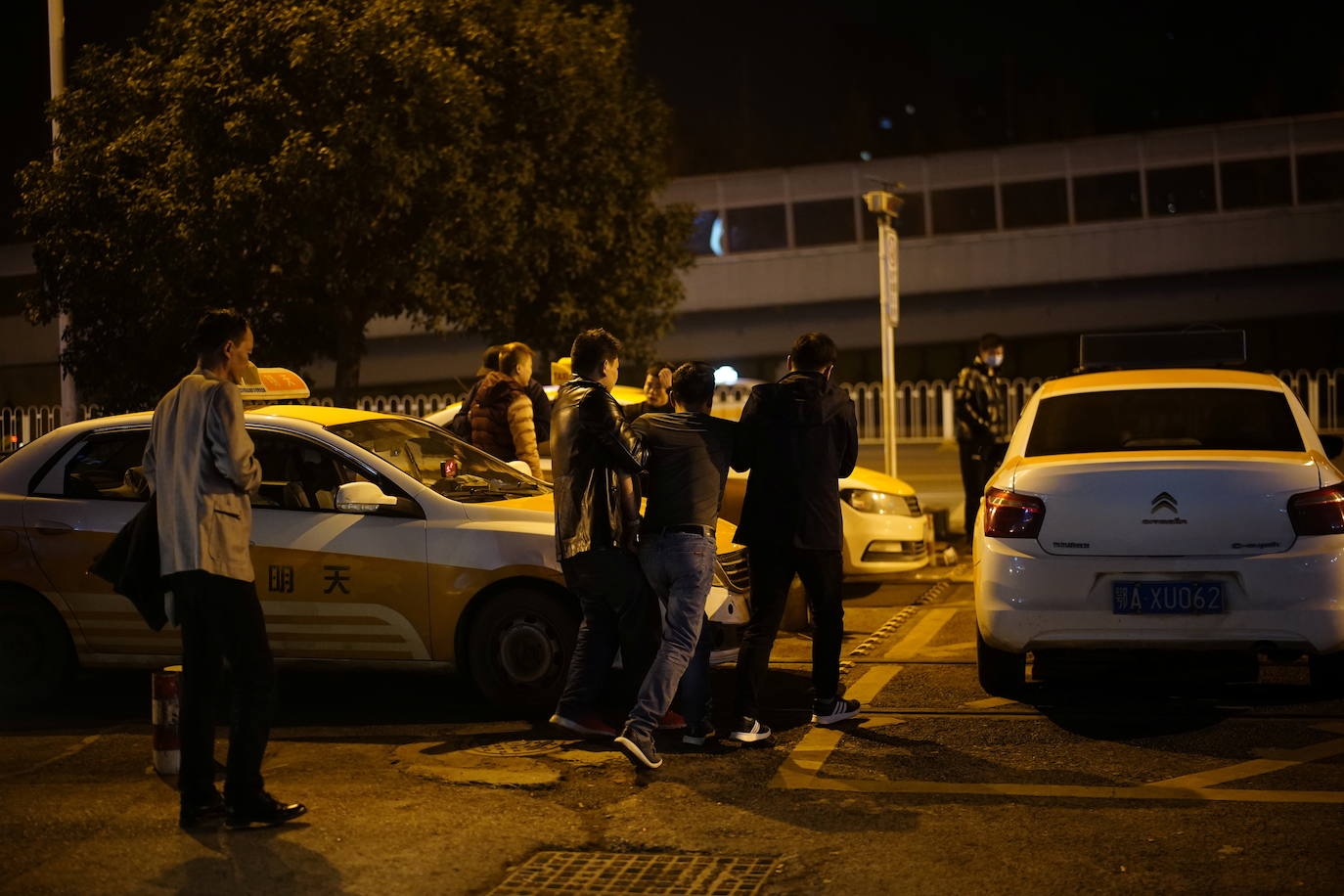 Un hombre es ayudado por amigos a subirse a un taxi frente a un club nocturno.