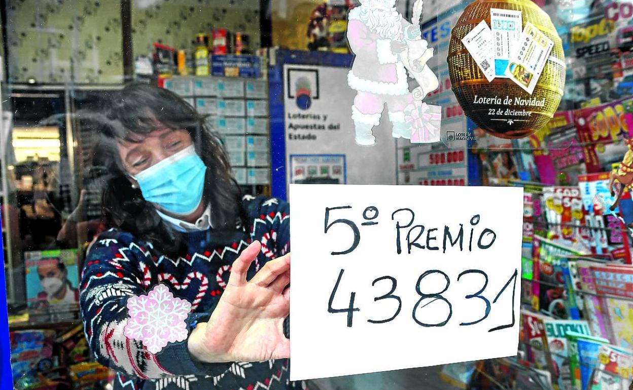 Lourdes Atiega coloca el cartel con el número que llevó la suerte a su estanco. 